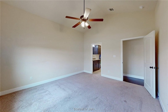 unfurnished bedroom with visible vents, high vaulted ceiling, ensuite bath, carpet, and baseboards