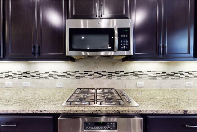 kitchen with light stone counters, backsplash, and stainless steel appliances