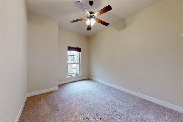 carpeted empty room featuring baseboards and a ceiling fan