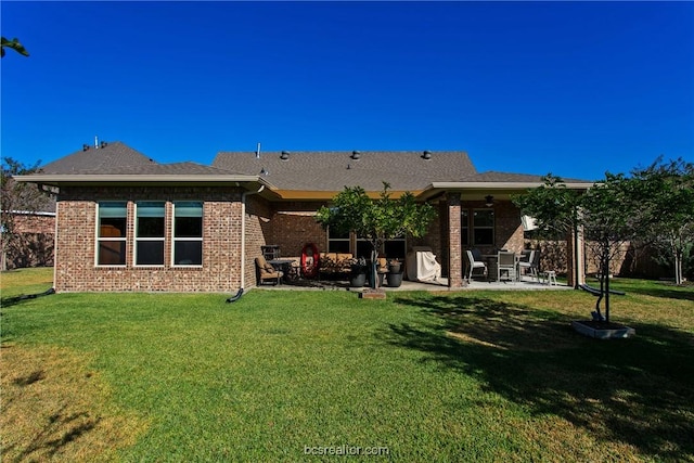 back of property with a yard, brick siding, and a patio area