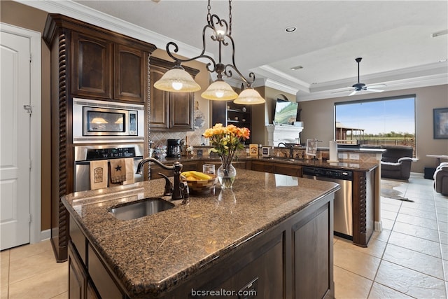 kitchen with appliances with stainless steel finishes, dark brown cabinetry, sink, a center island with sink, and hanging light fixtures