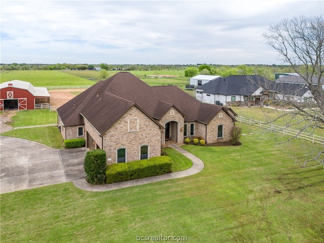 view of front of home with a rural view, an outdoor structure, and a front lawn