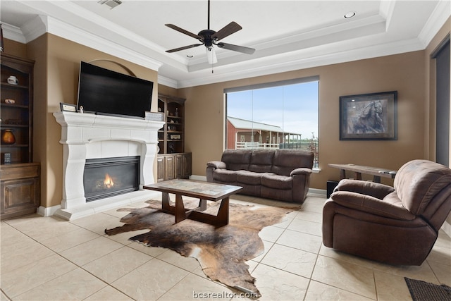 living room featuring ceiling fan, light tile patterned flooring, a raised ceiling, and crown molding