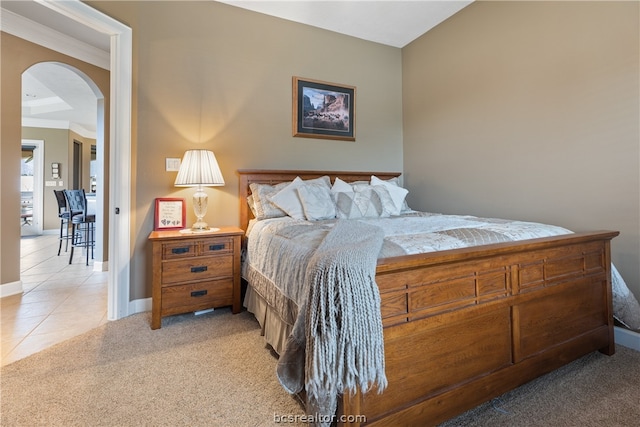 bedroom with ornamental molding and light carpet