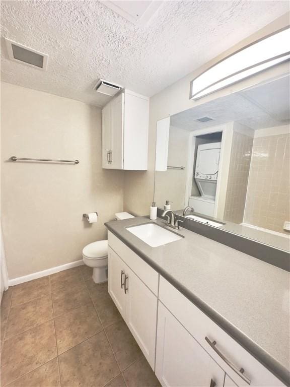 bathroom with tile patterned flooring, vanity, a textured ceiling, and toilet