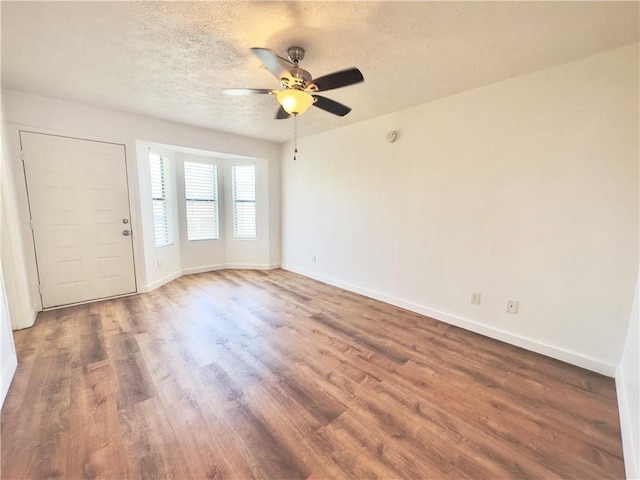 spare room with a textured ceiling, dark hardwood / wood-style flooring, and ceiling fan