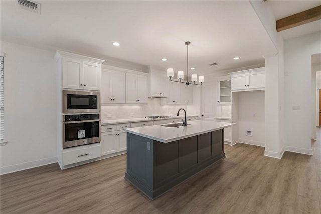 kitchen featuring appliances with stainless steel finishes, a kitchen island with sink, sink, white cabinets, and hardwood / wood-style floors