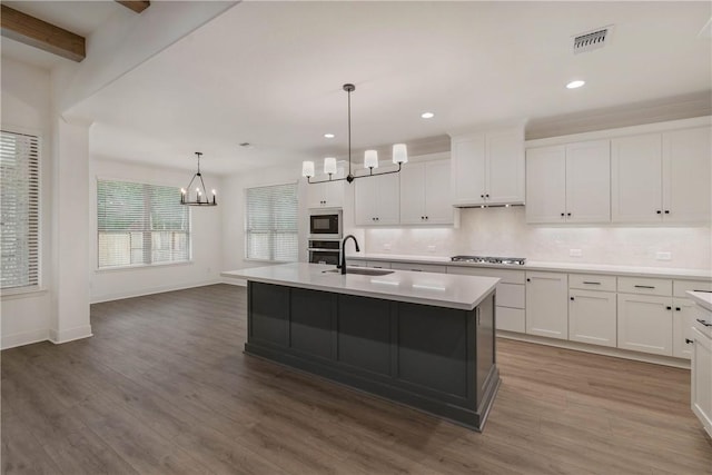 kitchen featuring a center island with sink, sink, hardwood / wood-style floors, and appliances with stainless steel finishes