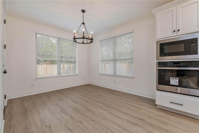 interior space with stainless steel oven, black microwave, a notable chandelier, light hardwood / wood-style floors, and white cabinetry