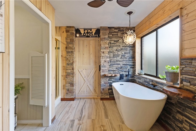 bathroom featuring plus walk in shower, wood walls, and hardwood / wood-style flooring