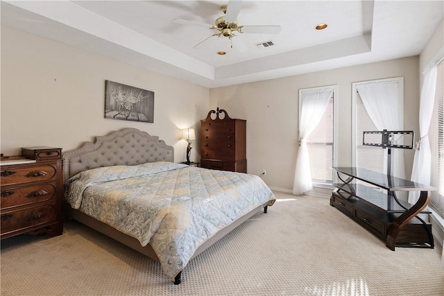 carpeted bedroom featuring ceiling fan and a tray ceiling