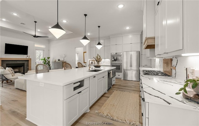 kitchen with a spacious island, decorative light fixtures, light hardwood / wood-style floors, white cabinetry, and stainless steel appliances