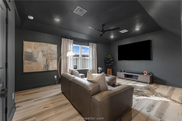 cinema room with ceiling fan, vaulted ceiling, and light hardwood / wood-style flooring