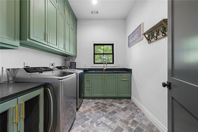 laundry room featuring visible vents, washing machine and clothes dryer, a sink, brick floor, and cabinet space