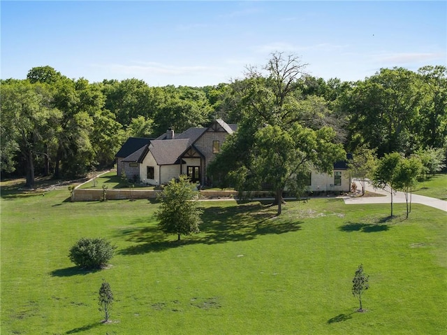 view of front of property with a view of trees, a chimney, and a front yard