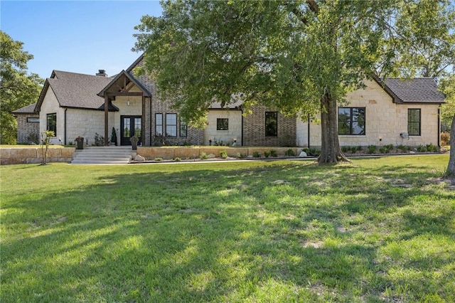 view of front of property with a front yard, stone siding, and a chimney