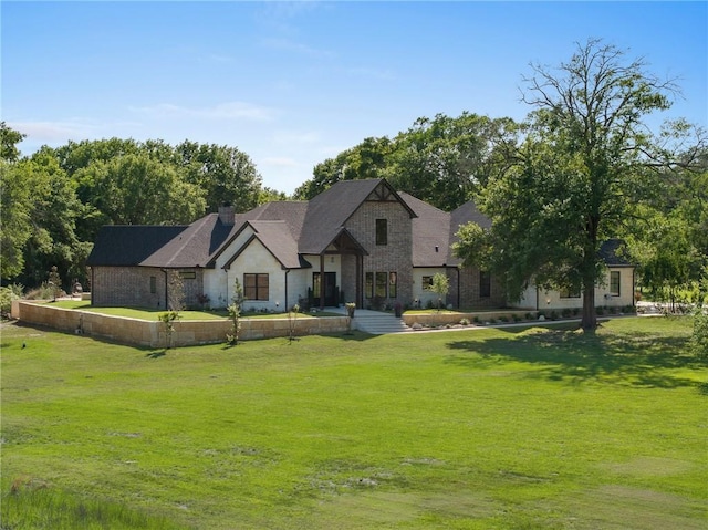 modern farmhouse style home with a front yard, stone siding, and a chimney