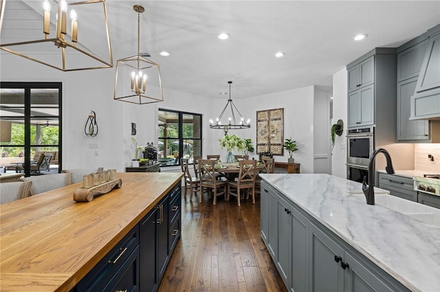 kitchen featuring a notable chandelier, dark wood-style flooring, gray cabinets, recessed lighting, and butcher block counters