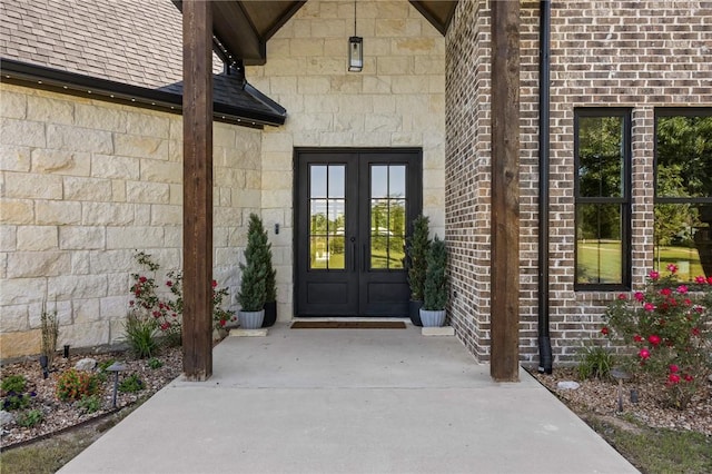 entrance to property featuring roof with shingles and french doors
