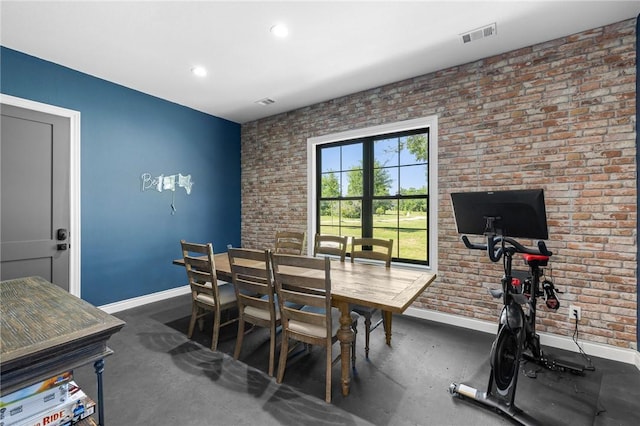 dining space featuring brick wall, baseboards, visible vents, and concrete floors