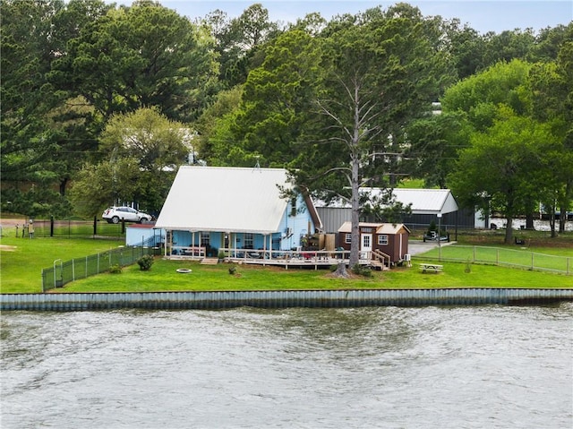 rear view of house featuring a lawn, fence, and a water view