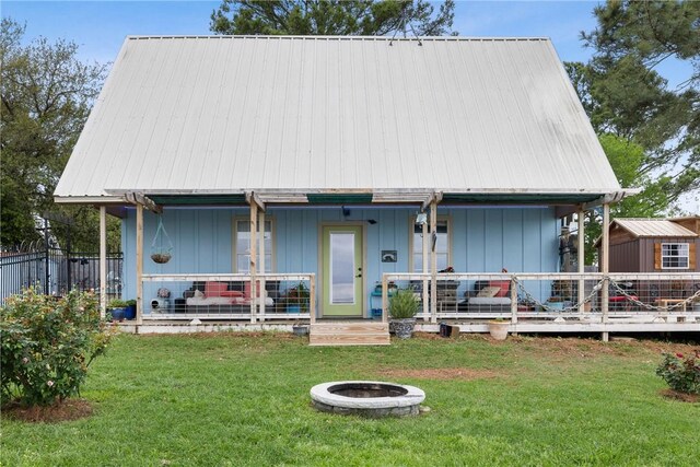 rear view of house with a yard, fence, a fire pit, and covered porch