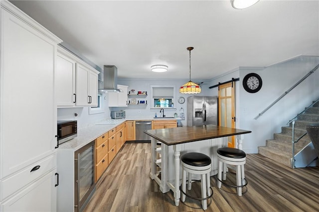 kitchen featuring range hood, open shelves, a barn door, a sink, and stainless steel appliances