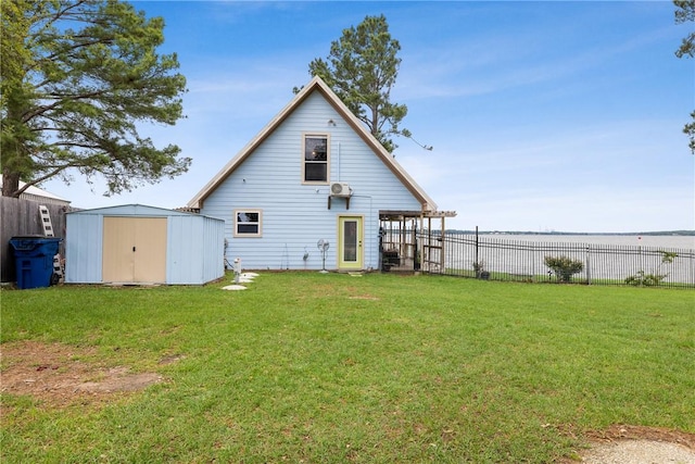 rear view of property with a yard, a shed, fence, and an outbuilding