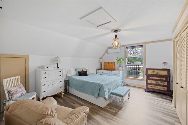 bedroom featuring wood finished floors, attic access, and vaulted ceiling