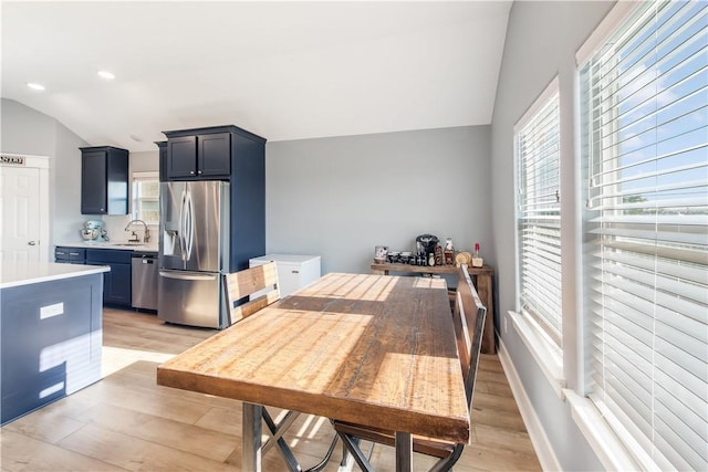 dining area featuring vaulted ceiling, sink, and light hardwood / wood-style flooring