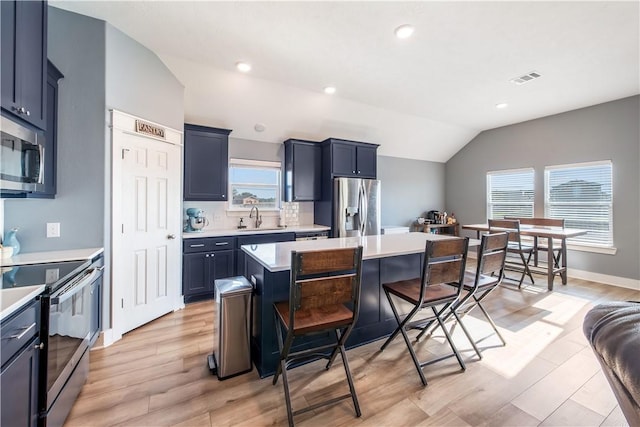 kitchen featuring a center island, sink, a wealth of natural light, appliances with stainless steel finishes, and a kitchen bar