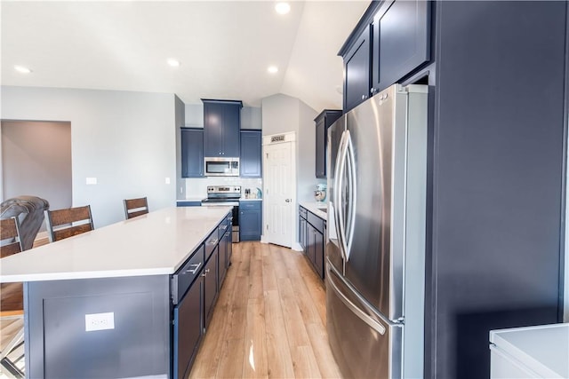 kitchen with a kitchen island, light hardwood / wood-style floors, a breakfast bar area, and appliances with stainless steel finishes