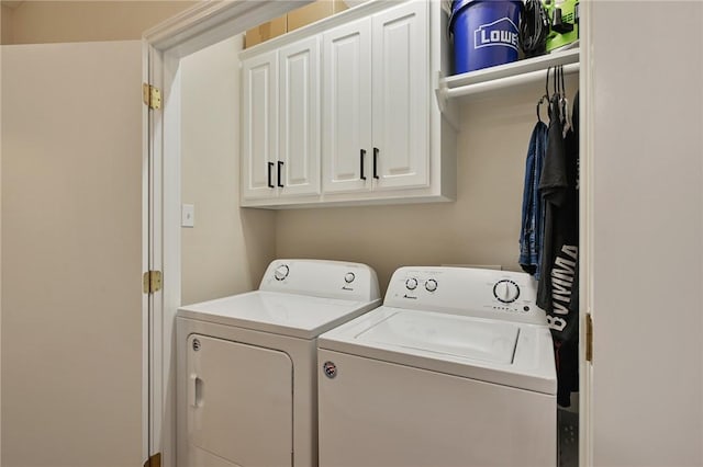 clothes washing area with washer and clothes dryer and cabinets