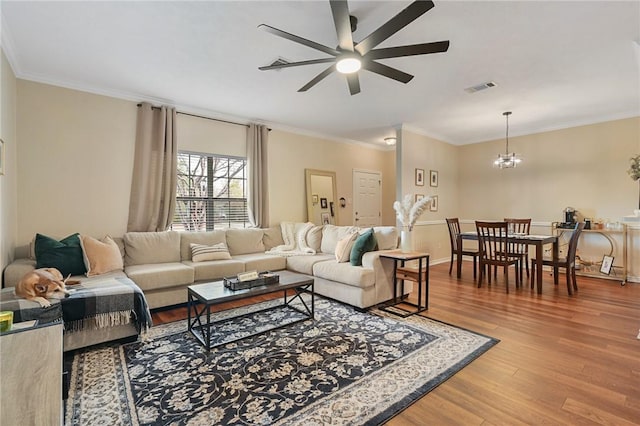 living room with hardwood / wood-style floors, ceiling fan with notable chandelier, and ornamental molding