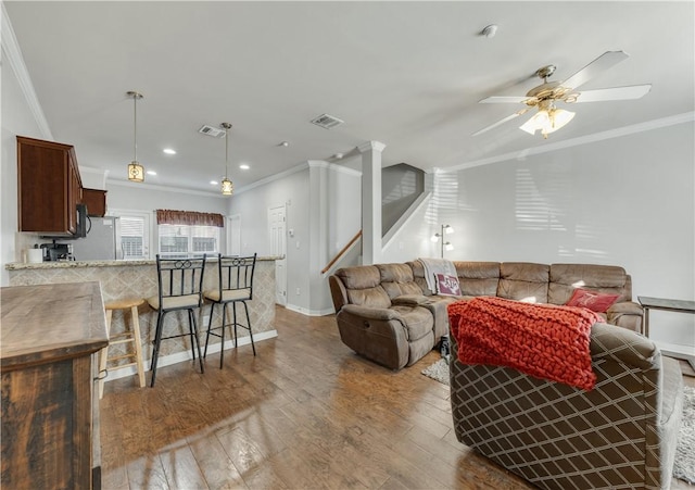 living room featuring wood-type flooring, ceiling fan, and ornamental molding