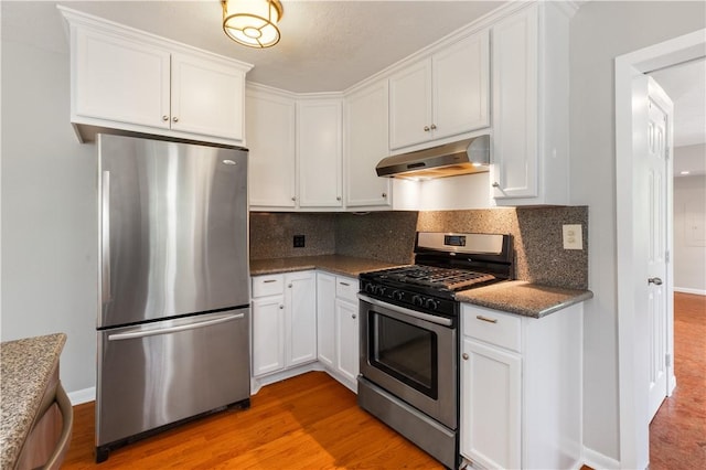 3907 Nagle St N, Bryan, TX 77801 - kitchen featuring appliances with stainless steel finishes, under cabinet range hood, white cabinets, and tasteful backsplash