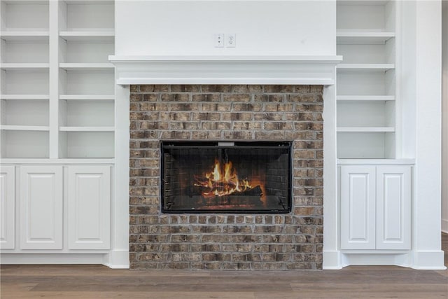 interior details with hardwood / wood-style floors, built in features, and a brick fireplace