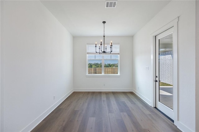 unfurnished dining area with wood-type flooring and a notable chandelier