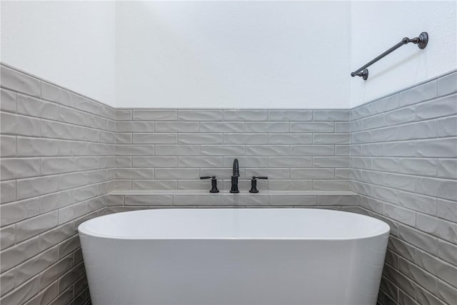 bathroom with a washtub and tile walls