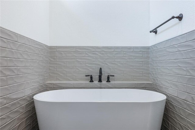 bathroom with a washtub and tile walls