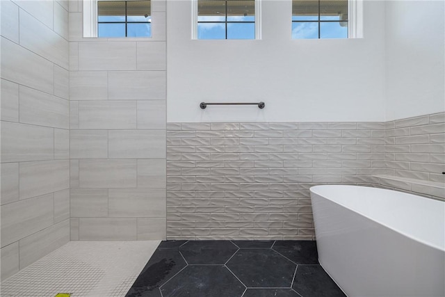 bathroom with tile patterned flooring, separate shower and tub, tile walls, and a healthy amount of sunlight