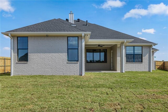 rear view of property featuring a lawn and ceiling fan