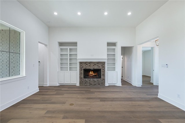 unfurnished living room with dark hardwood / wood-style flooring and a brick fireplace