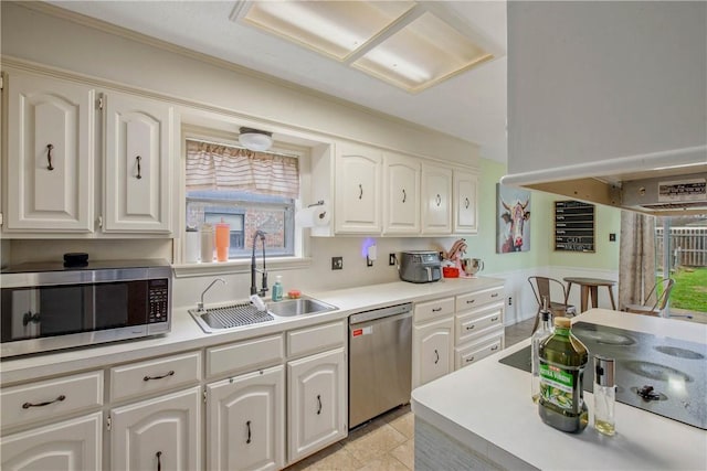 kitchen featuring appliances with stainless steel finishes, light countertops, a sink, and white cabinetry