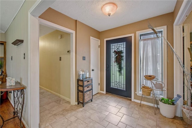 foyer entrance with baseboards and a textured ceiling