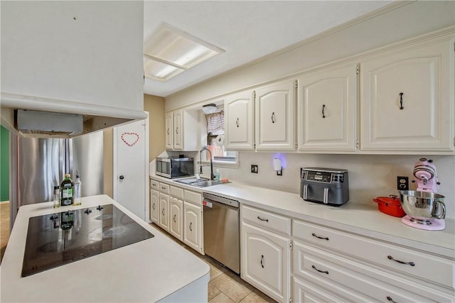 kitchen featuring stainless steel appliances, light countertops, a sink, and white cabinetry