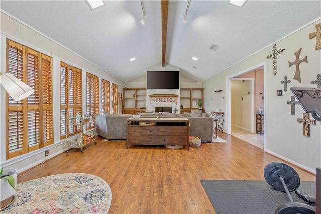 living area featuring lofted ceiling with beams, light wood-style flooring, visible vents, baseboards, and a brick fireplace