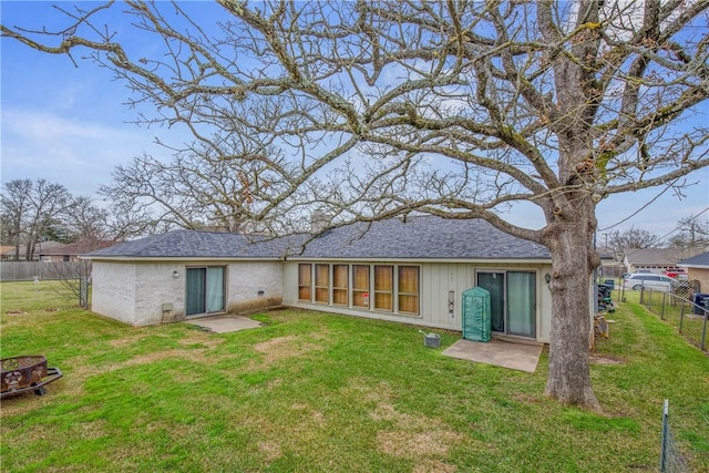 rear view of property with a yard, roof with shingles, and fence