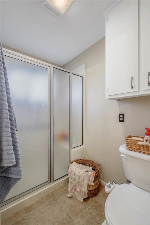 full bath featuring baseboards, a shower stall, toilet, and tile patterned floors