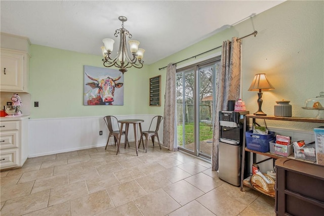 dining area featuring a wainscoted wall and an inviting chandelier